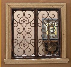 an ornate iron window on the side of a building with a glass door in it