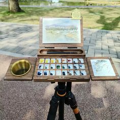 an artist's easel on a tripod with watercolors in it