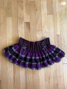 a purple and black skirt laying on top of a wooden floor