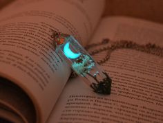 an open book with a glowing necklace on it