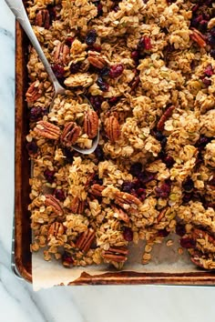 granola on a baking sheet with a spoon in it, ready to be eaten