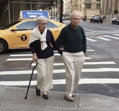 an older couple walking down the street with their canes in hand and holding hands