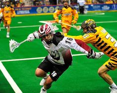 two men in uniforms playing lacrosse on a field