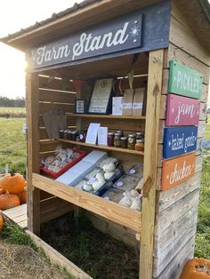 a small wooden stand with food items on it and pumpkins in the grass behind it