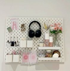 a white shelf filled with lots of items on top of a wall next to flowers