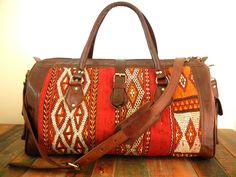 "Pair up with the perfect companion for your next adventure. Our 'Atlas' duffle (Tribal Red) is crafted from a repurposed, vintage wool kilim; beautifully handwoven by the Berber peoples of the Atlas mountains. Limited Edition - you will receive one of only 9 made from this vintage, hand-loomed Kilim (shown). These truly unique, one of a kind beauties are skillfully crafted by our artisans in Marrakech. Each Kilim yields a limited number of unique bags so you are guaranteed to have a special tre Bohemian Leather Tote Duffle Bag, Bohemian Leather Duffle Bag For Trips, Bohemian Brown Duffle Bag For Weekend Trips, Bohemian Brown Duffle Bag With Leather Handles, Brown Bohemian Duffle Bag With Leather Handles, Bohemian Leather Travel Bag With Leather Handles, Bohemian Leather Weekender Bag For Trips, Bohemian Brown Weekender Bag For Overnight Trips, Brown Bohemian Weekender Bag For Overnight Trips