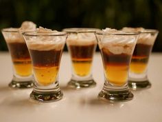 four shot glasses filled with ice cream and liquid sitting on a white table top next to each other