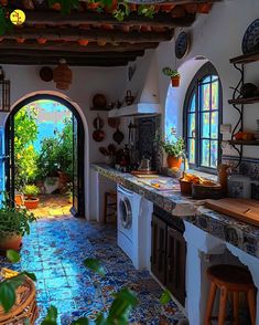 a kitchen with an arched doorway leading to the outside patio and outdoor pool in the background