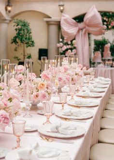 a long table is set up with pink flowers and candles for an elegant wedding reception