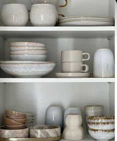 the shelves are filled with dishes and cups