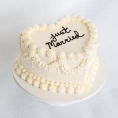 a heart shaped cake with the words happy married written on it's side, sitting on a white plate