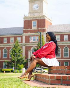 a woman sitting on the steps in front of a building with a clock tower behind her