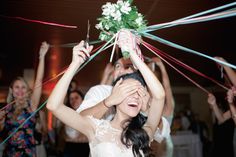 a bride and groom dancing with streamers in front of their faces at a wedding