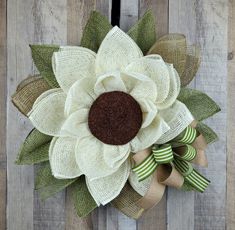 a white and brown flower with green leaves on a wooden fence post ornament