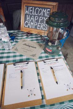 a table topped with notebooks and paper next to a sign that says welcome happy campers