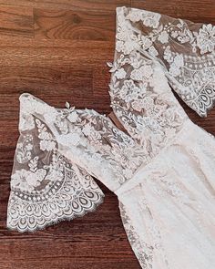 two pieces of white lace sitting on top of a wooden floor