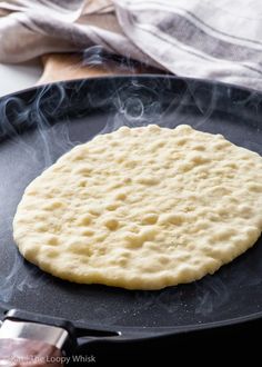 an uncooked flat bread is being cooked in a skillet on the stove