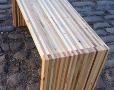 a wooden bench sitting on top of a cobblestone road