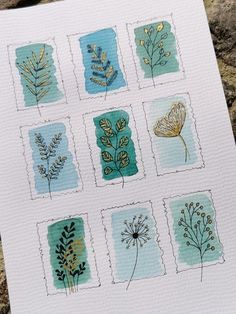 a card with different types of flowers and leaves on it's front, sitting on top of a rock