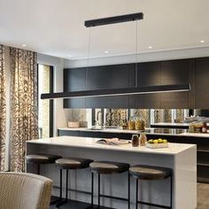 a kitchen with an island and bar stools in front of it, along with curtains on the windows