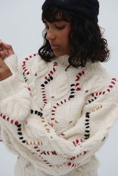 This cozy sweater is a true standout with its hand-knit design and eye-catching details. . Made from baby alpaca and merino wool, it showcases a high crew neckline, blending casual comfort with a polished appearance. The diamond cable-knit pattern, accented with bold multicolor embroidery adds a playful yet artisanal flair. The textured knit, combined with voluminous balloon sleeves, makes this sweater both cozy and fashion-forward. Its slightly cropped, relaxed fit offers versatility for pairin Handknit Design, Multicolor Embroidery, Knitwear Inspiration, Yarn For Sale, Poncho Tops, Alpaca Sweater, Cozy Sweater, Mens Pajamas, Knit Pattern