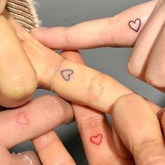 three fingers with hearts tattooed on them