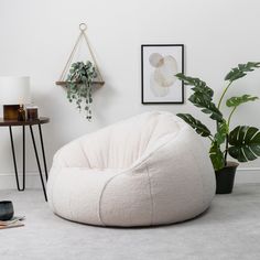 a white bean bag chair sitting on top of a floor next to a potted plant