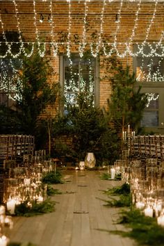 an outdoor wedding setup with candles and greenery on the ground, surrounded by brick walls