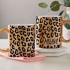 two leopard print coffee mugs sitting next to each other on a white counter top