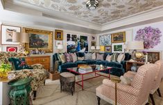 a living room filled with lots of furniture and paintings on the wall above it's windows