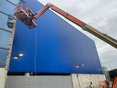 a large blue building being worked on by a crane