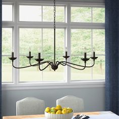 a chandelier hanging over a dining room table with lemons and apples on it