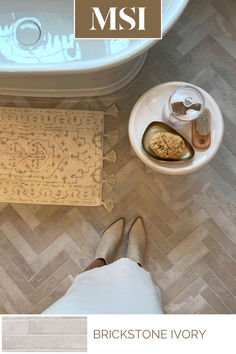 a person standing in front of a bath tub next to a rug on the floor