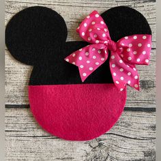 a minnie mouse head with pink and white polka dots on it, sitting on a wooden surface