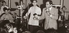 black and white photograph of two men singing into microphones in front of an audience