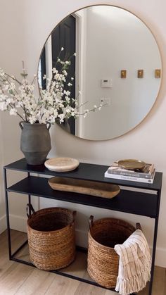 a black console table with two baskets and a round mirror