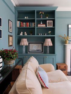 a living room filled with furniture and a fire place next to a wall mounted book shelf