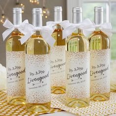 five bottles of wine are sitting on a table with gold and white decorations around them