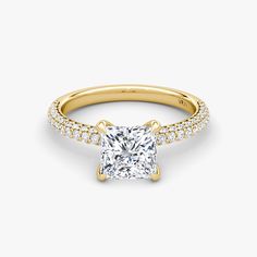 a gold engagement ring with a princess cut diamond and pave set diamonds around the band