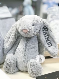 a gray stuffed rabbit sitting on top of a table