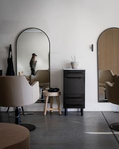 a room with mirrors, stools and chairs in it