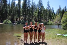 four girls in bathing suits standing on the shore of a lake