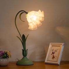 a lamp that is on top of a table next to a vase with flowers in it