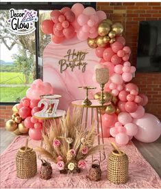 a pink and gold birthday party with balloons, cake, candles and decorations on the table