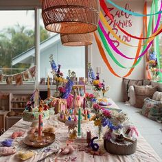 a table covered with lots of colorful streamers and decorations in front of a window