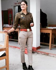 a woman in uniform standing next to a wooden chair and smiling at the camera with one hand on her hip