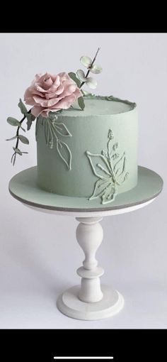 there is a green cake with flowers on the top and bottom tier, sitting on a white pedestal