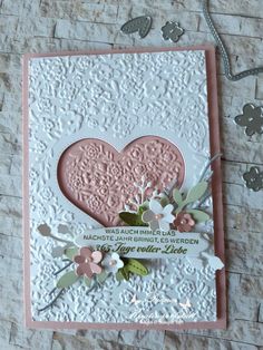 a close up of a card on a table with flowers and hearts in the background