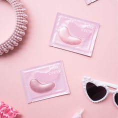 three pairs of heart shaped sunglasses on top of a pink surface next to pearls and other accessories