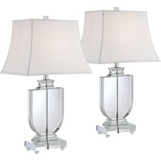 two clear glass lamps with white shades on them